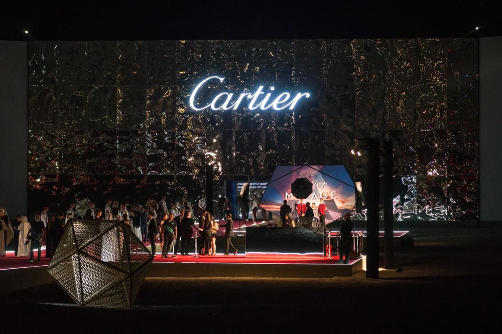 La scène de l'événement Cartier Mirage : enseigne lumineuse sur mur miroir et écran diffusant le film.