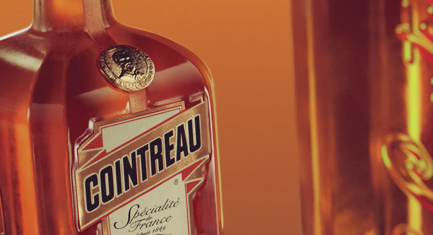 Flacon Cointreau historique reconstitué en images de synthèse : étiquette dorée, médaillon au col et mention Spécialité de France depuis 1849.