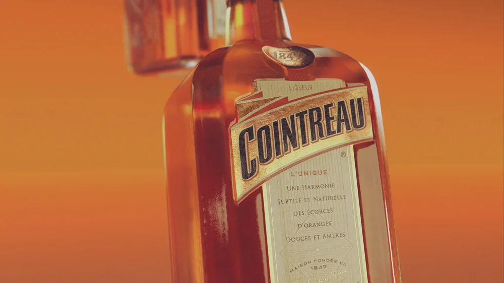 Flacon Cointreau en 3D, étiquette « L'Unique », plan large sur le col et le sceau doré.