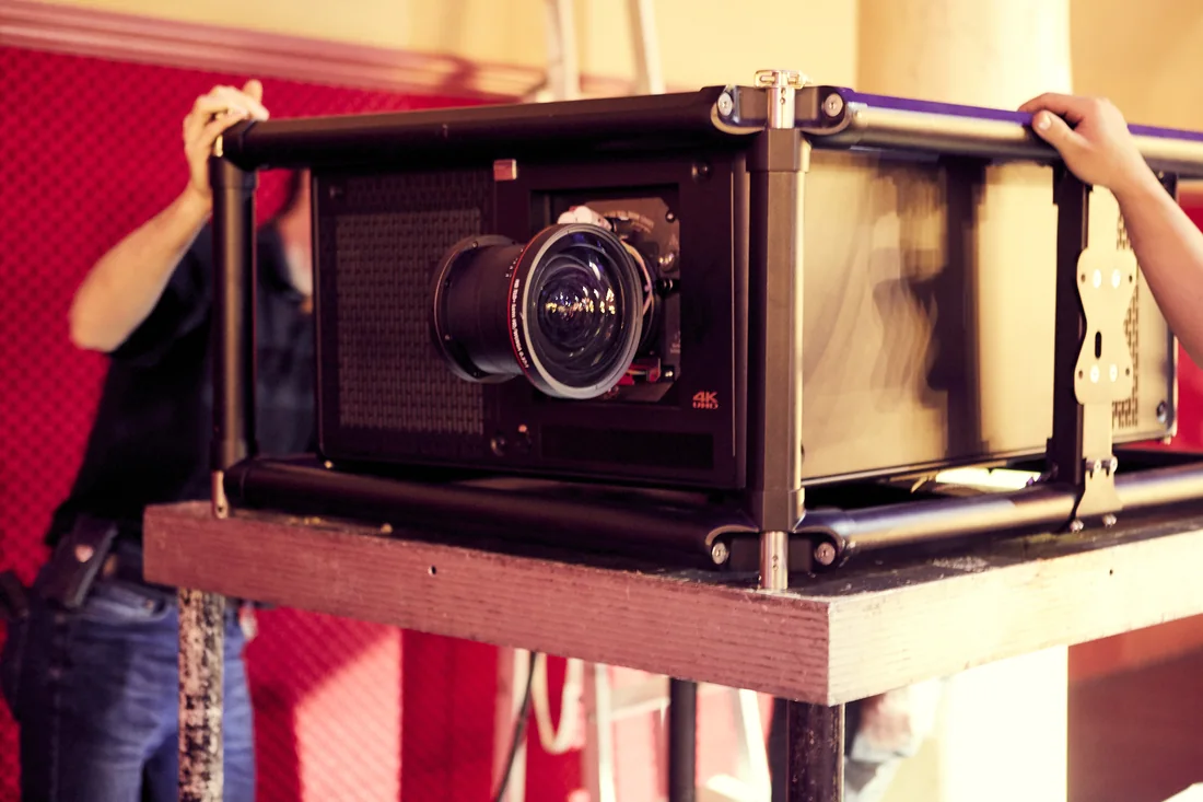 Installation d'un projecteur 4K en salle, avant la diffusion du contenu de la cérémonie.