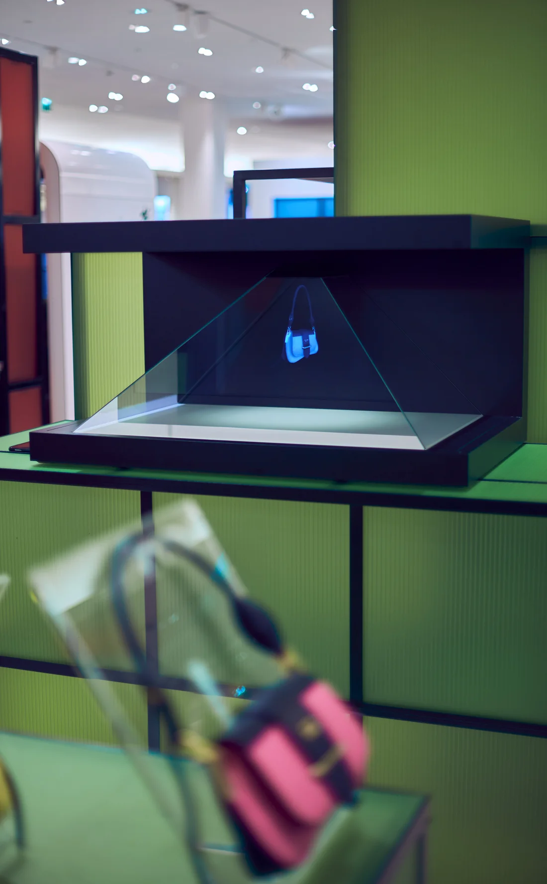 Borne holographique Prada en boutique, sac à main présenté en hologramme au-dessus du socle.