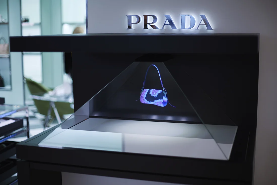 Gros plan sur l'hologramme du sac Prada Sidonie, sous l'enseigne de la Maison en vitrine.