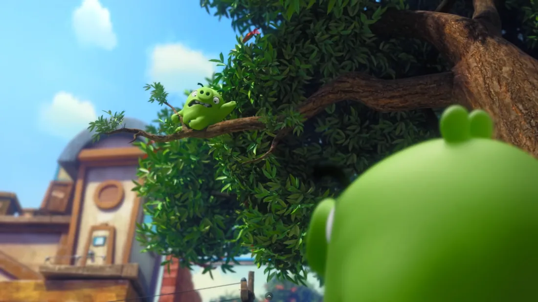 Rendu 3D d'un personnage animé vert dans un arbre, en gros plan, ambiance de village illustré à l'arrière-plan.
